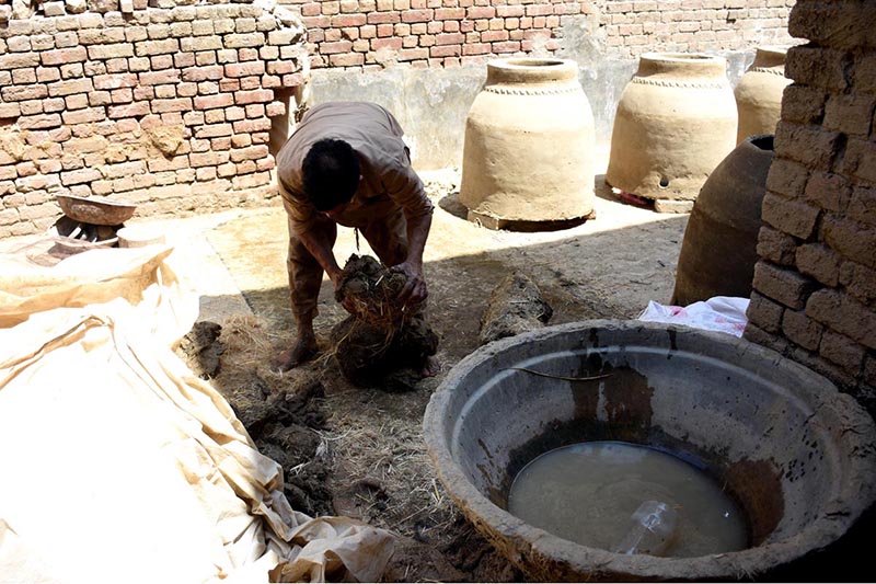 A laborer mixes natural clay and organic binders at a workshop to prepare raw material for traditional tandoor ovens