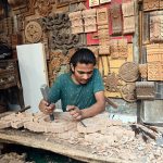 A young craftsman carves wood at his workplace