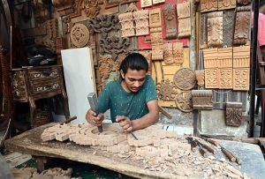 A young craftsman carves wood at his workplace