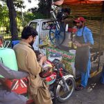 A vendor serves sugarcane juice to customers on a hot day in the city at Stadium Road
