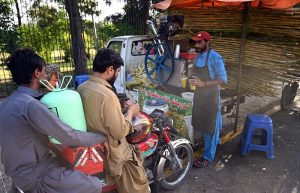A vendor serves sugarcane juice to customers on a hot day in the city at Stadium Road