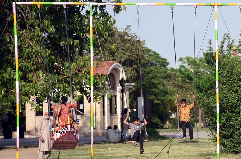 Children are seen enjoying swings at Greater Iqbal Park