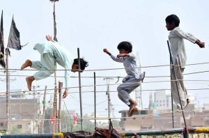 Gypsy children enjoying jump on trampoline at Latifabad area.