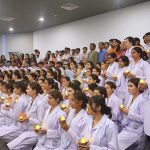 Male and female nurses hold candles while participating in a lamp-lighting ceremony on International Nurses Day at Ziauddin University
