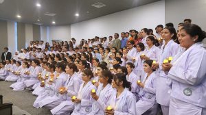 Male and female nurses hold candles while participating in a lamp-lighting ceremony on International Nurses Day at Ziauddin University