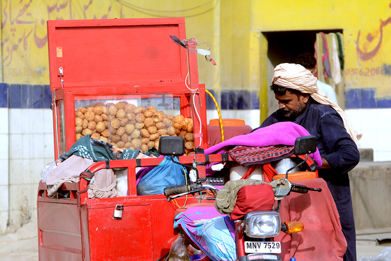 A man sells gol gappay from a motorcycle to earn his livelihood