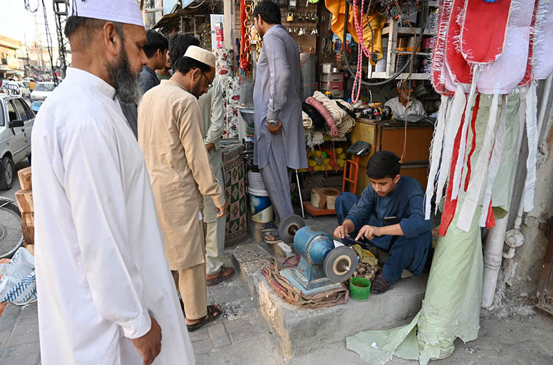 A blacksmith is busy sharpening knives and axes to be used for slaughtering sacrificial animals during Eid ul Azha