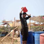 A boy throws water on his body to protect himself from the intense heat at the Bhatta Chowk livestock market