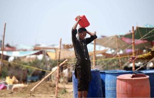 A boy throws water on his body to protect himself from the intense heat at the Bhatta Chowk livestock market