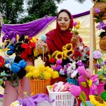 A female vendor displays and sells artificial decorative flowers at her stall during the Hunar Mela organized by KP Culture & Tourism Authority at Nishtar Hall