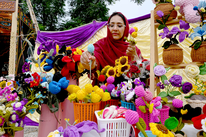 A female vendor displays and sells artificial decorative flowers at her stall during the Hunar Mela organized by KP Culture & Tourism Authority at Nishtar Hall