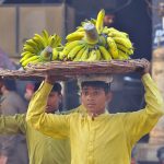 Young daily wage workers carry baskets of bananas on their heads for supply while the world observes International Labour Day
