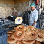 A worker prepares and arranges freshly baked tandoori bakarkhani to attract customers