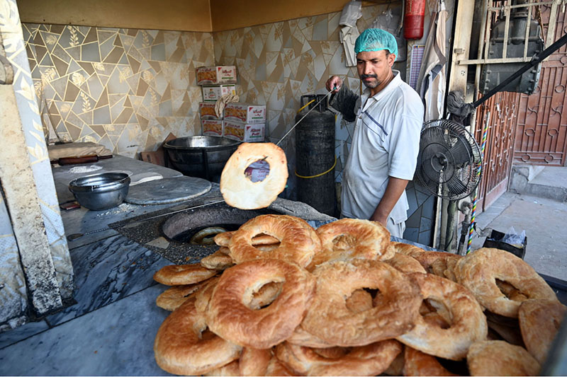 A worker prepares and arranges freshly baked tandoori bakarkhani to attract customers