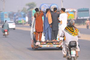 People travel while hanging on a passenger van on a busy NLC bypass road, putting their lives in risk and prompting the need for concerned authorities to take notice of the widespread violation