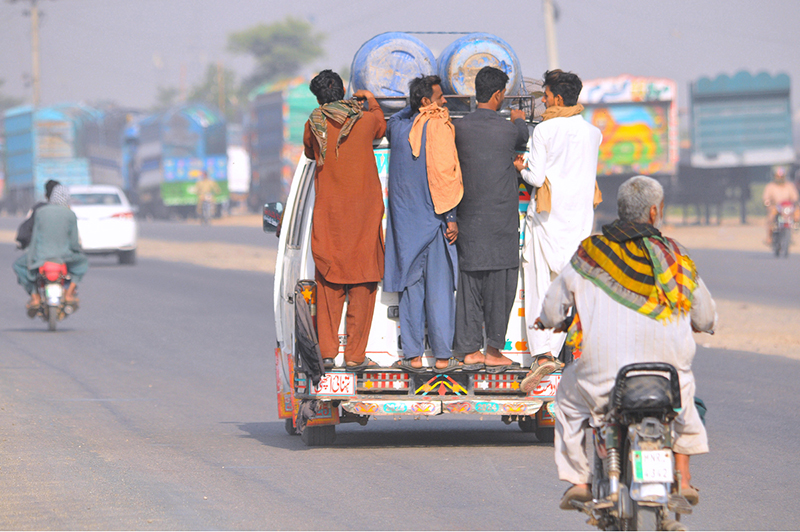 People travel while hanging on a passenger van on a busy NLC bypass road, putting their lives in risk and prompting the need for concerned authorities to take notice of the widespread violation