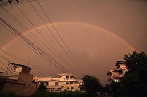 A vibrant rainbow arches over residential buildings in the city, creating a picturesque moment for residents.