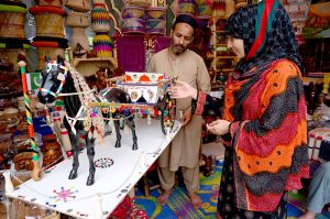 A female vendor displays and sells artificial decorative flowers at her stall during the Hunar Mela organized by KP Culture & Tourism Authority at Nishtar Hall