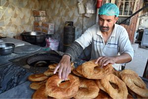 A worker prepares and arranges freshly baked tandoori bakarkhani to attract customers
