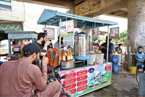 A roadside vendor preparing a Sikanjabeen (traditional lemonade) or similar cold drink for a customer, likely to beat the heat.