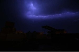 A striking view of lightning flashing across the sky during rainfall, illuminating the dark clouds.