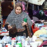 A woman purchases used kitchen items from a vendor at Empress Market