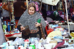 A woman purchases used kitchen items from a vendor at Empress Market