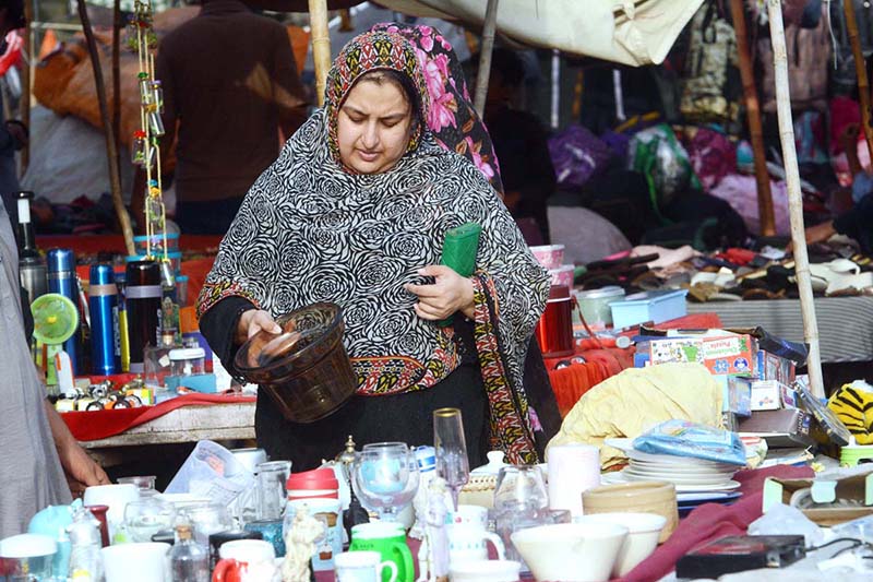 A woman purchases used kitchen items from a vendor at Empress Market
