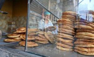 A worker prepares and arranges freshly baked tandoori bakarkhani to attract customers