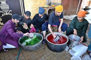 Members of the Hindu community distribute chilled summer drinks to the public outside Hindu Dharamshala on a hot day, offering relief to passersby in the city.
