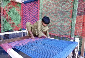 A boy busy in preparing traditional bed (Charpai) at his workplace.