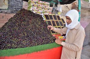A street vendor displays fresh cherries on his push cart at Pishin Stop, drawing the attention of passersby and consumers.