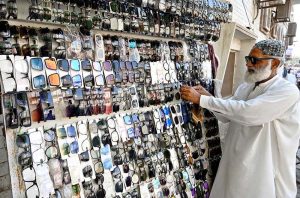 An elderly vendor sells glasses at his roadside stall on Qaim Shah Bukhari Road