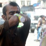 A disabled man drinks a sweet beverage from a volunteer-run camp set up during hot weather conditions