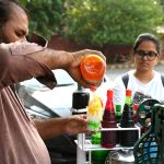A vendor busy in preparing and selling Ice Gola to the customers on the roadside setup
