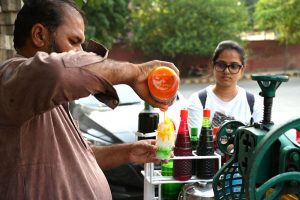 A vendor busy in preparing and selling Ice Gola to the customers on the roadside setup