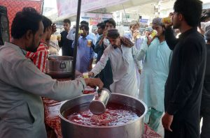 A disabled man drinks a sweet beverage from a volunteer-run camp set up during hot weather conditions