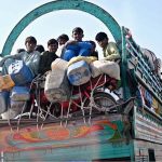People travel on the edge of an overloaded truck on Larkana-Khairpur Road, posing a risk of accidents and calling for the attention of concerned authorities