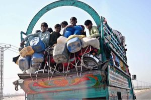 People travel on the edge of an overloaded truck on Larkana-Khairpur Road, posing a risk of accidents and calling for the attention of concerned authorities
