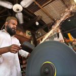 blacksmith is busy sharpening knives and axes to be used for slaughtering sacrificial animals during Eid ul Azha