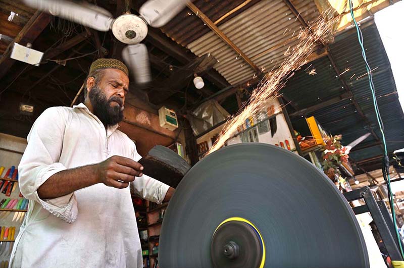 blacksmith is busy sharpening knives and axes to be used for slaughtering sacrificial animals during Eid ul Azha