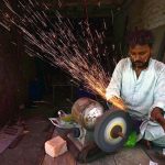 A worker sharpens knives used for sacrificial animals in connection with Eid-ul-Azha at fort road