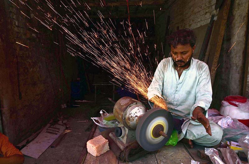 A worker sharpens knives used for sacrificial animals in connection with Eid-ul-Azha at fort road