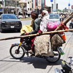 A gypsy family is shifting to another location on a motorbike with their belongings