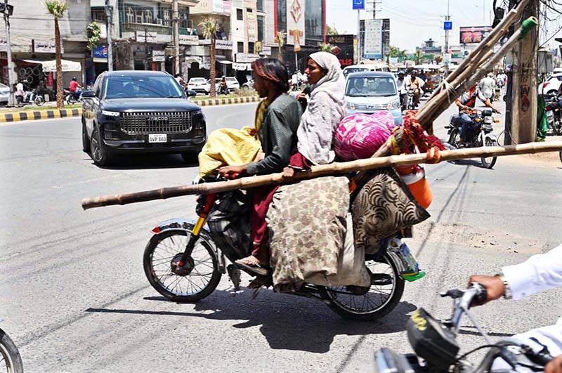 A gypsy family is shifting to another location on a motorbike with their belongings