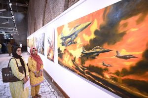 Visitors keenly viewing paintings on display marking the first anniversary of “Marka-e-Haq,” and the Successful operation Bunyan-al-Marsoos at NCA.