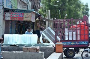 A labourer unloads large blocks of ice from a delivery rickshaw at a roadside stall as demand for ice rises amid the intense summer heat in the city.