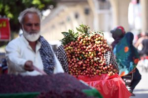 A street vendor sells fresh lychees and berries at a roadside at Murree Road, as the summer fruit season gets underway.