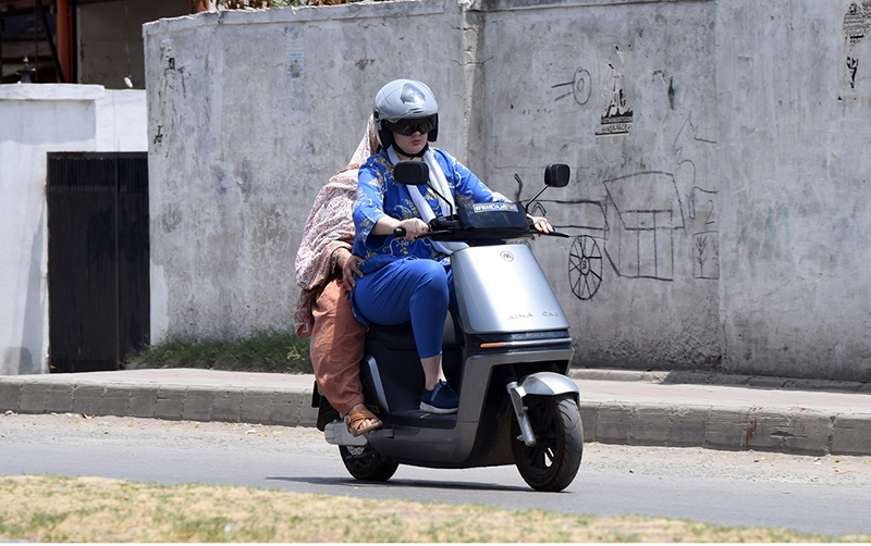 Women ride an electric scooter along Tipu Road in Rawalpindi, as more residents, particularly women, turn to affordable electric two-wheelers for daily commuting amid rising fuel costs