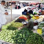 People busy purchasing vegetables from stall at I/9-4 weekly bazaar in Federal Capital